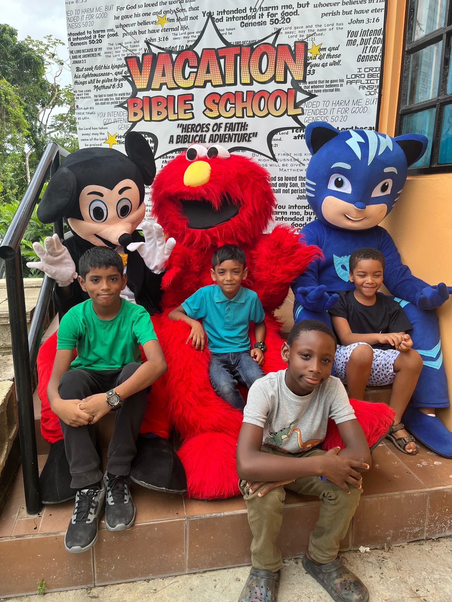 Kids with costumed characters including Mickey Mouse and Elmo at VBS 2025 Fun Day